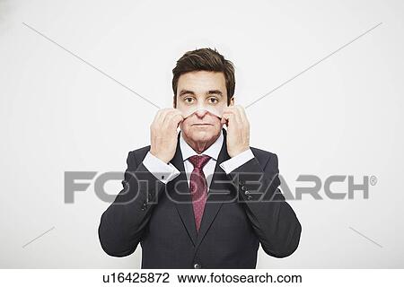 Stock Image - Businessman pulling on mask. Fotosearch