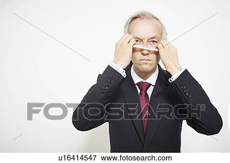 Stock Photo - Businessman pulling on mask. Fotosearch