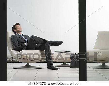Businessman sitting in office lobby View Large Photo Image Stock Image - Businessman sitting in office lobby. Fotosearch