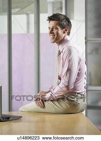 Businessman sitting on desk View Large Photo Image Stock Image - Businessman sitting on desk. Fotosearch