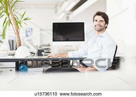 Businessman smiling at desk View Large Photo Image Stock Image - Businessman smiling at desk. Fotosearch