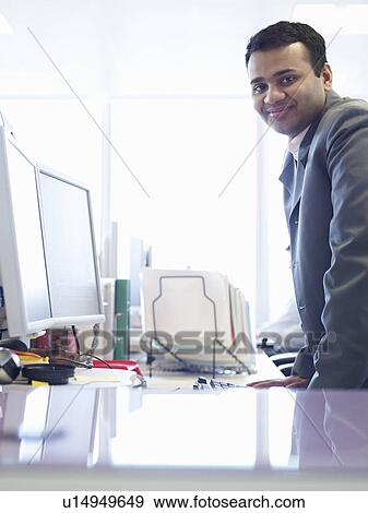 Businessman smiling at desk View Large Photo Image Stock Photo - Businessman smiling at desk. Fotosearch