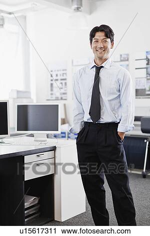 Stock Image - Businessman smiling in office. Fotosearch