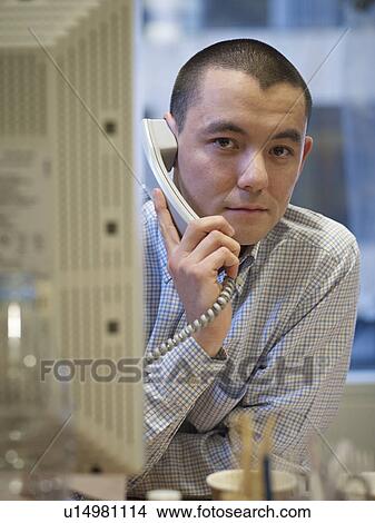 Businessman talking on phone at desk View Large Photo Image Picture - Businessman talking on phone at desk. Fotosearch