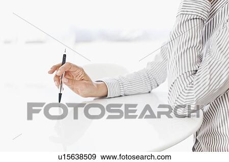 Businessman tapping pen on desk View Large Photo Image Stock Photo - Businessman tapping pen on desk. Fotosearch