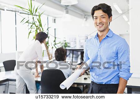 Businessman with blueprints in office View Large Photo Image Stock Photo - Businessman with blueprints in office. Fotosearch