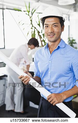 Businessman with blueprints in office View Large Photo Image Stock Photo - Businessman with blueprints in office. Fotosearch