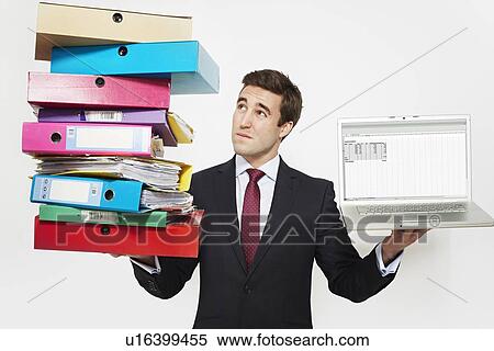 Stock Photography - Businessman with stacks of folders and laptop. Fotosearch
