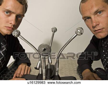 Stock Image - Businessmen talking into microphones. Fotosearch