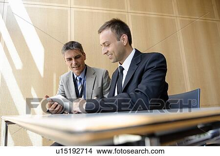 Businessmen using tablet computer at desk View Large Photo Image Picture - Businessmen using tablet computer at desk. Fotosearch