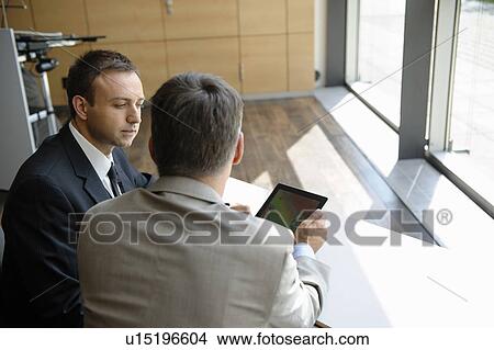Businessmen using tablet computer at desk View Large Photo Image Picture - Businessmen using tablet computer at desk. Fotosearch