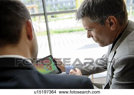 Businessmen using tablet computer at desk View Large Photo Image Picture - Businessmen using tablet computer at desk. Fotosearch