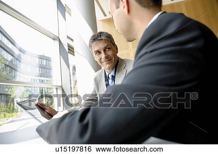 Businessmen using tablet computer at desk View Large Photo Image Stock Photograph - Businessmen using tablet computer at desk. Fotosearch