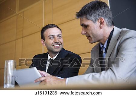 Businessmen using tablet computer at desk View Large Photo Image Stock Photography - Businessmen using tablet computer at desk. Fotosearch