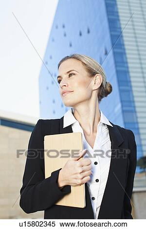Stock Photography - Businesswoman carrying folder outdoors. Fotosearch