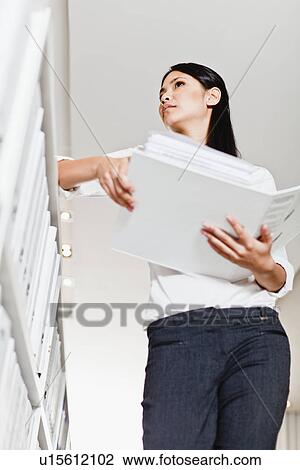 Businesswoman holding folder in library View Large Photo Image Stock Image - Businesswoman holding folder in library. Fotosearch