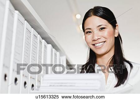 Businesswoman holding folder in library View Large Photo Image Stock Photography - Businesswoman holding folder in library. Fotosearch