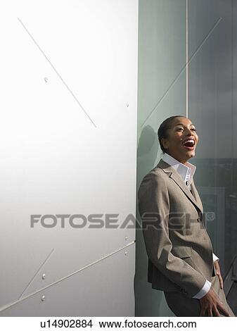 Picture - Businesswoman leaning on office wall. Fotosearch