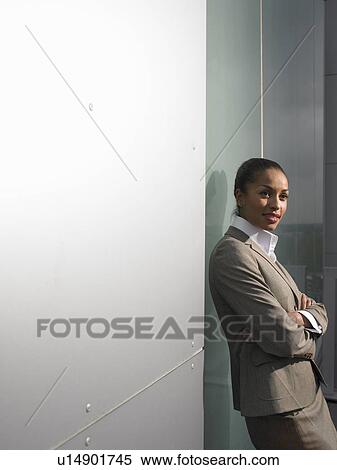 Stock Photography - Businesswoman leaning on office wall. Fotosearch