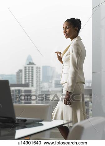 Businesswoman looking out office window View Large Photo Image Stock Image - Businesswoman looking out office window. Fotosearch