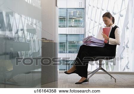 Businesswoman reading files in chair View Large Photo Image Stock Photo - Businesswoman reading files in chair. Fotosearch