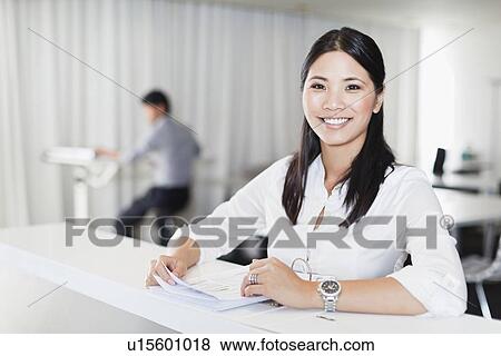 Stock Photo - Businesswoman smiling at desk. Fotosearch