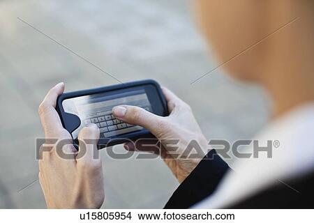 Picture - Businesswoman using cell phone outdoors. Fotosearch