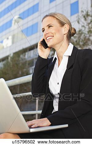 Stock Image - Businesswoman using laptop outdoors. Fotosearch