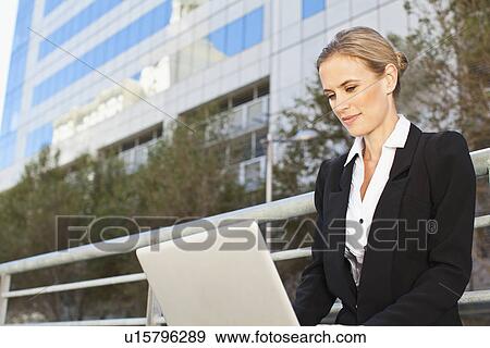 Stock Photo - Businesswoman using laptop outdoors. Fotosearch