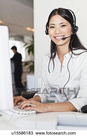 Businesswoman wearing headset at desk View Large Photo Image Stock Image - Businesswoman wearing headset at desk. Fotosearch