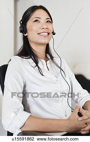 Businesswoman wearing headset at desk View Large Photo Image Stock Image - Businesswoman wearing headset at desk. Fotosearch