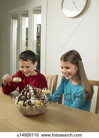 Stock Image - Children eating large bowl of ice cream. Fotosearch