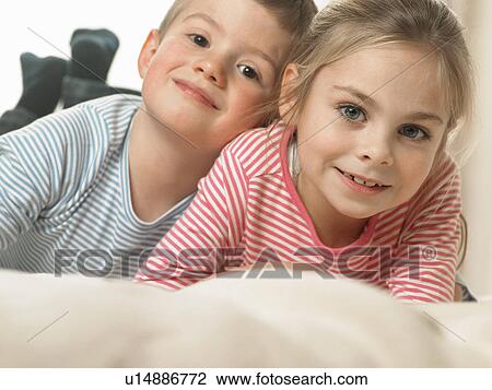 Stock Image - Children laughing together on bed. Fotosearch