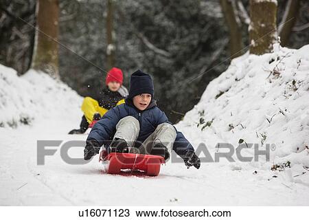 Stock Image - Children sledding on snowy slope. Fotosearch