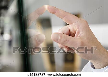 Stock Photo - Close up of hand touching glass panel. Fotosearch