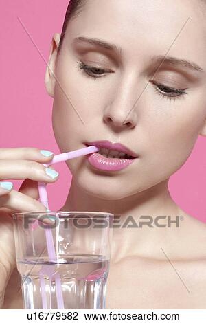 Stock Image - Close up of woman drinking with straw. Fotosearch