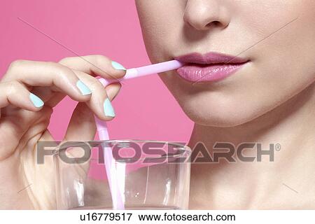 Stock Photo - Close up of woman drinking with straw. Fotosearch