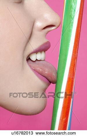 Stock Image - Close up of woman licking candy. Fotosearch