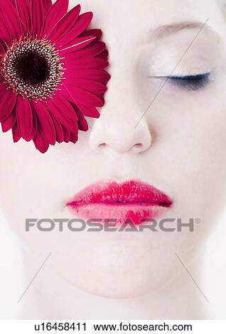 Stock Image - Close up of womans face with flower. Fotosearch