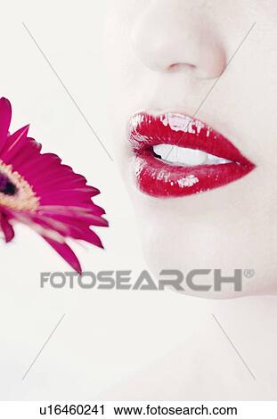 Stock Image - Close up of womans face with flower. Fotosearch