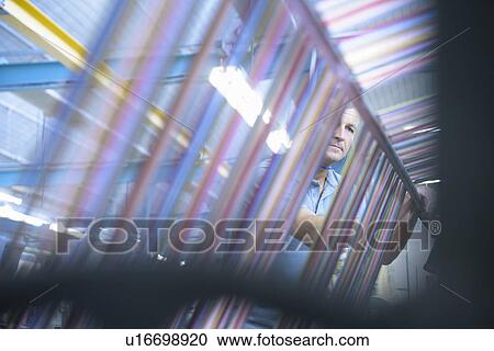 Stock Image - Colorful yarn on loom in textile mill. Fotosearch