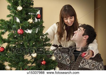 Stock Photo - Couple decorating Christmas tree. Fotosearch