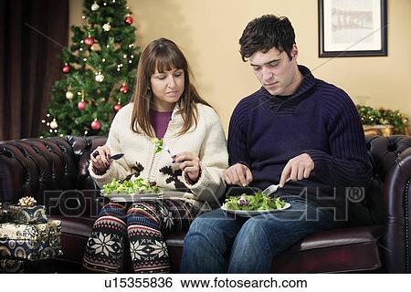 Stock Photograph - Couple eating salad on sofa. Fotosearch
