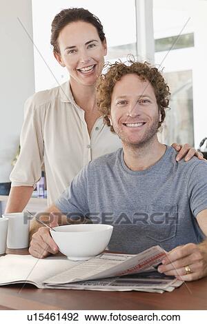 Stock Image - Couple reading newspaper at breakfast. Fotosearch