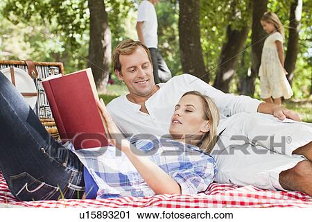 Couple relaxing on blanket in park View Large Photo Image Stock Image - Couple relaxing on blanket in park. Fotosearch