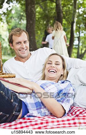 Couple relaxing on blanket in park View Large Photo Image Stock Image - Couple relaxing on blanket in park. Fotosearch