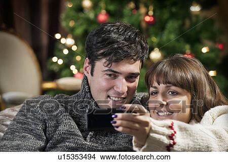 Picture - Couple taking cell phone picture on sofa. Fotosearch