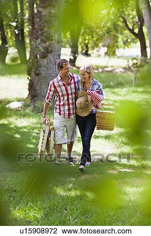 Stock Image - Couple with picnic basket in park. Fotosearch