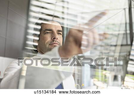 Picture - Doctor pointing to glass panel. Fotosearch