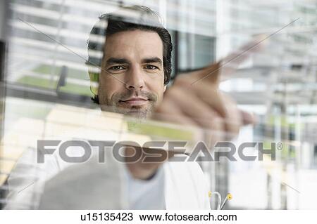 Stock Image - Doctor pointing to glass panel. Fotosearch